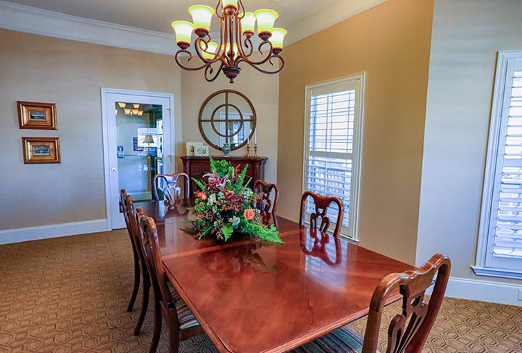 A stylish dining room featuring a wooden table adorned with a floral centerpiece, elegant chairs, and a classic chandelier overhead.