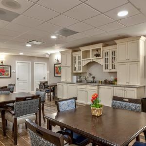 A cozy dining area with tables and chairs, adjacent to a modern kitchen space.