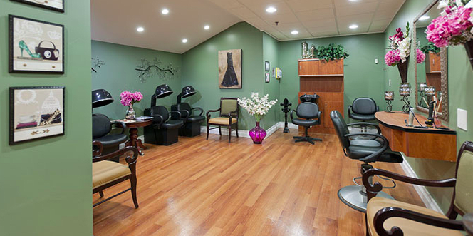 A cozy salon interior featuring comfortable chairs, hair dryers, and stylish decor against green walls.