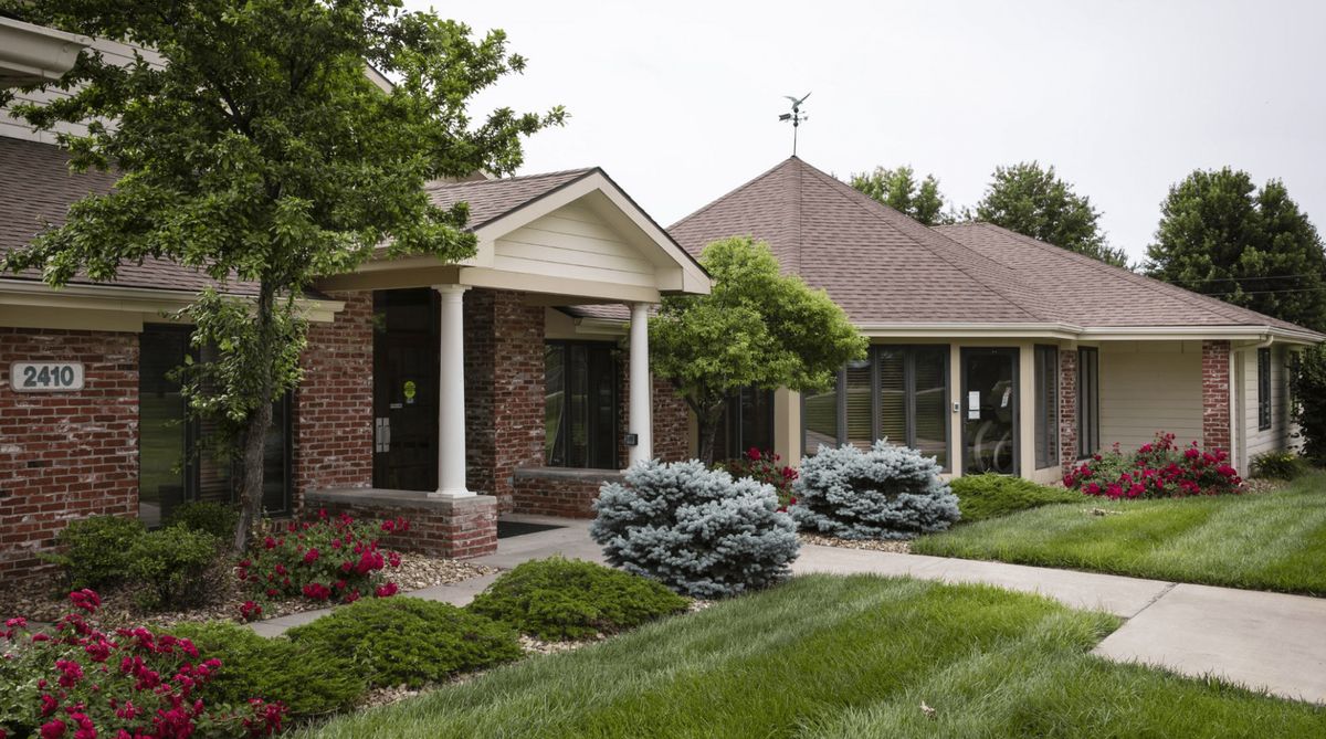 A suburban brick house with well-maintained landscaping and a lush green lawn.