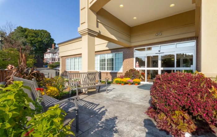 The entrance of a building featuring landscaped flower beds and seating.