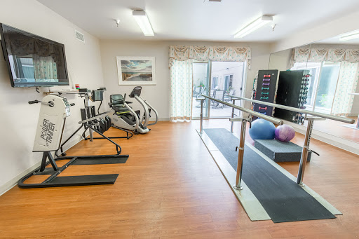 A modern fitness and rehabilitation room equipped with various exercise machines, balance bars, and stability balls.