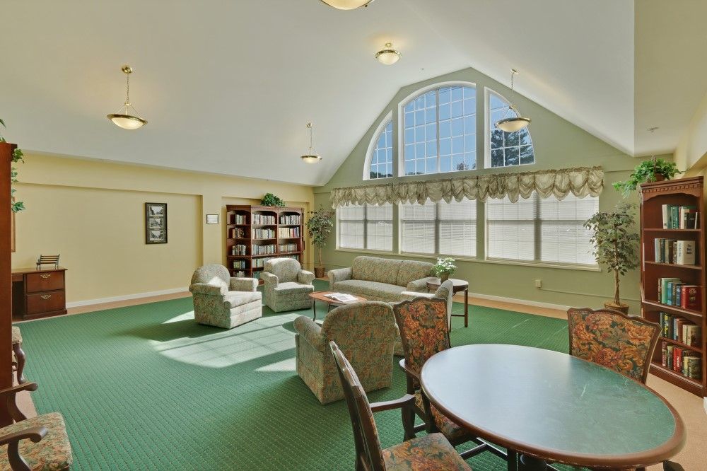 A cozy living room with ample seating, large windows, and a small library area.