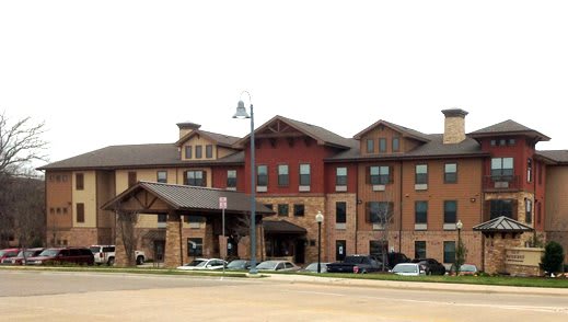 A modern hotel building with parked cars in front, showcasing a blend of traditional and contemporary architectural styles.
