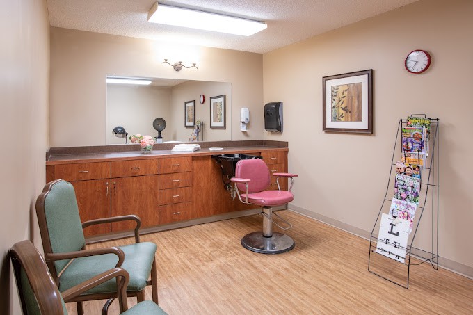 An empty hair salon with a styling chair, large mirror, and wooden cabinetry.