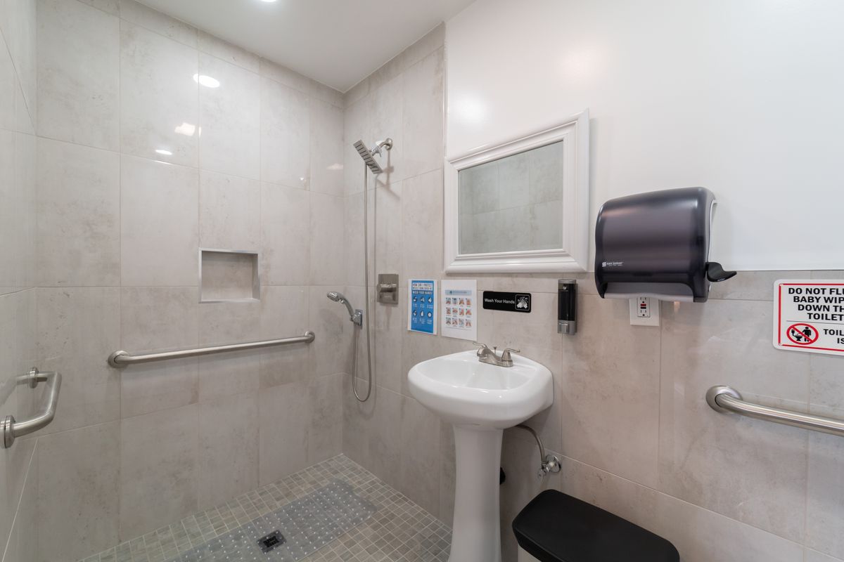 A clean, handicap-accessible bathroom with a pedestal sink and shower area.