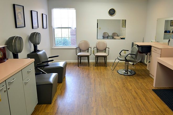 A cozy salon interior with styling chairs, a hair dryer, and a waiting area.