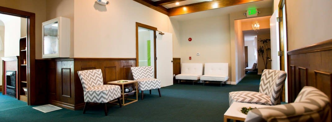 An empty waiting room with chairs and a carpeted floor.