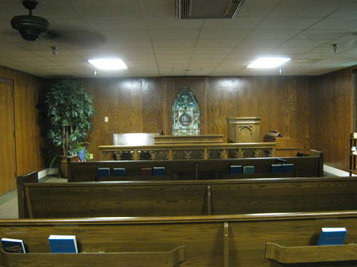 Interior view of a quiet church with wooden pews and an altar.
