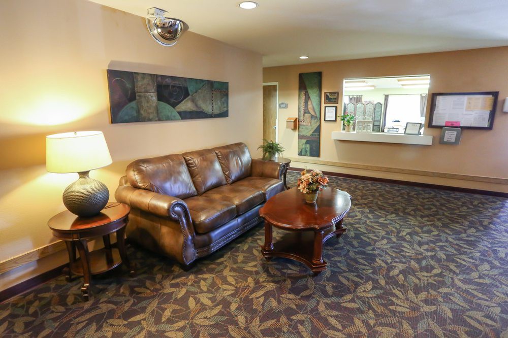 A lobby area featuring a leather sofa, coffee table, and art on the walls, with a reception desk in the background.