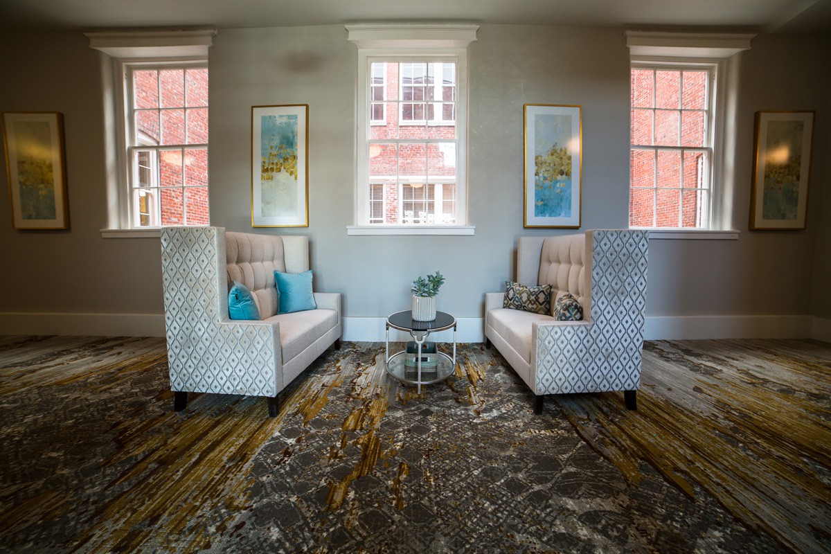 A cozy living room with matching armchairs, colorful pillows, and wall art.