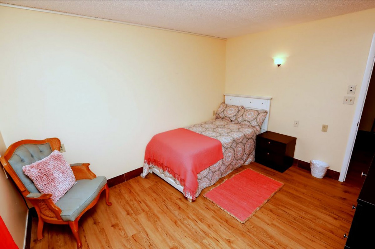 A cozy bedroom with a single bed, chair, and wooden flooring.