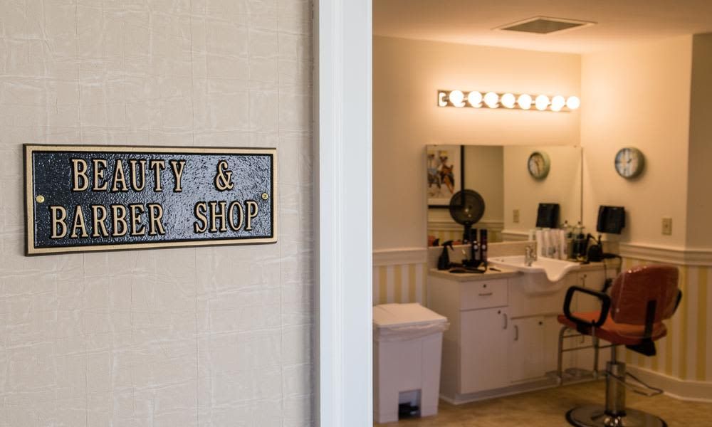 An interior view of a beauty and barber shop with a lighted mirror and styling station.