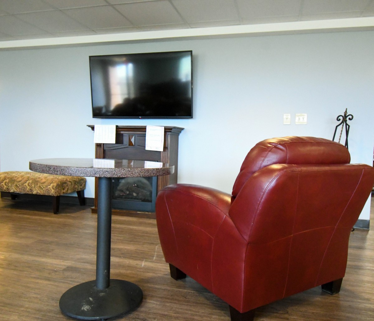 A cozy lounge area with a red chair, table, and mounted television.