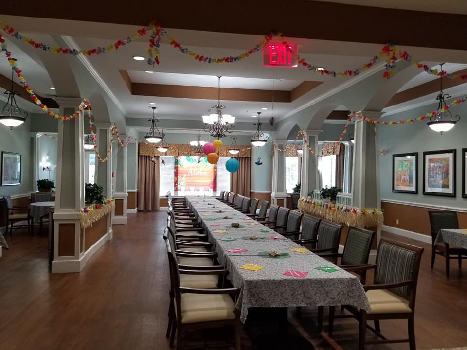 A decorated dining room prepared for a festive event, featuring a long table with chairs and colorful balloons and garlands.