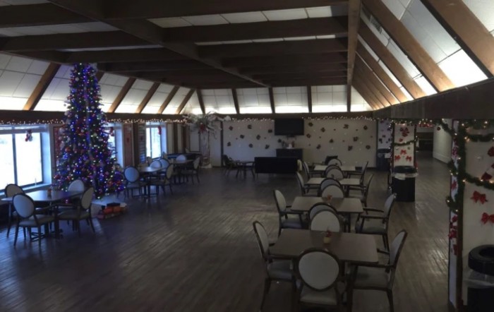 A decorated dining area with tables and chairs, featuring a Christmas tree.