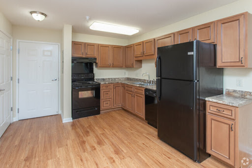 A modern kitchen featuring black appliances, wood cabinets, and granite countertops.