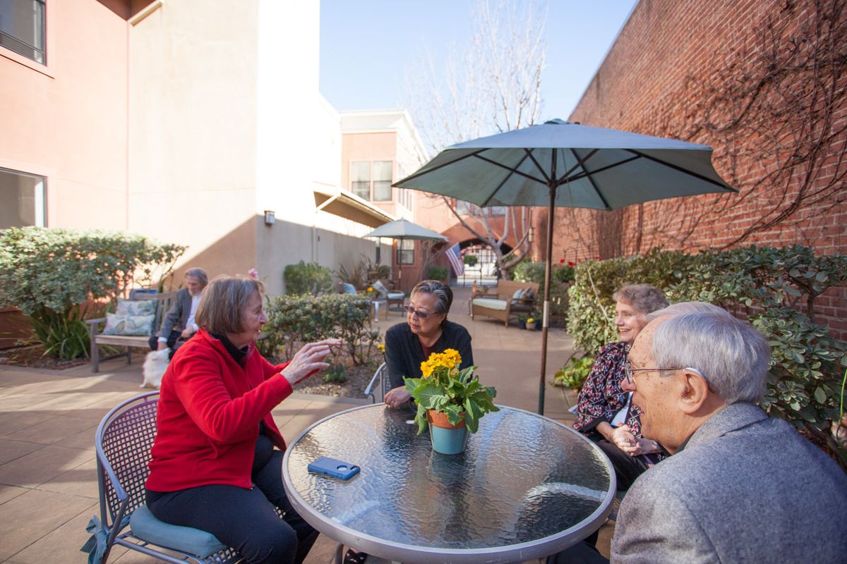 A group of people enjoying a conversation on a sunny patio.
