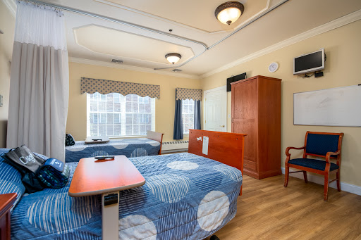 A well-lit hospital patient room featuring two beds and modern furnishings.