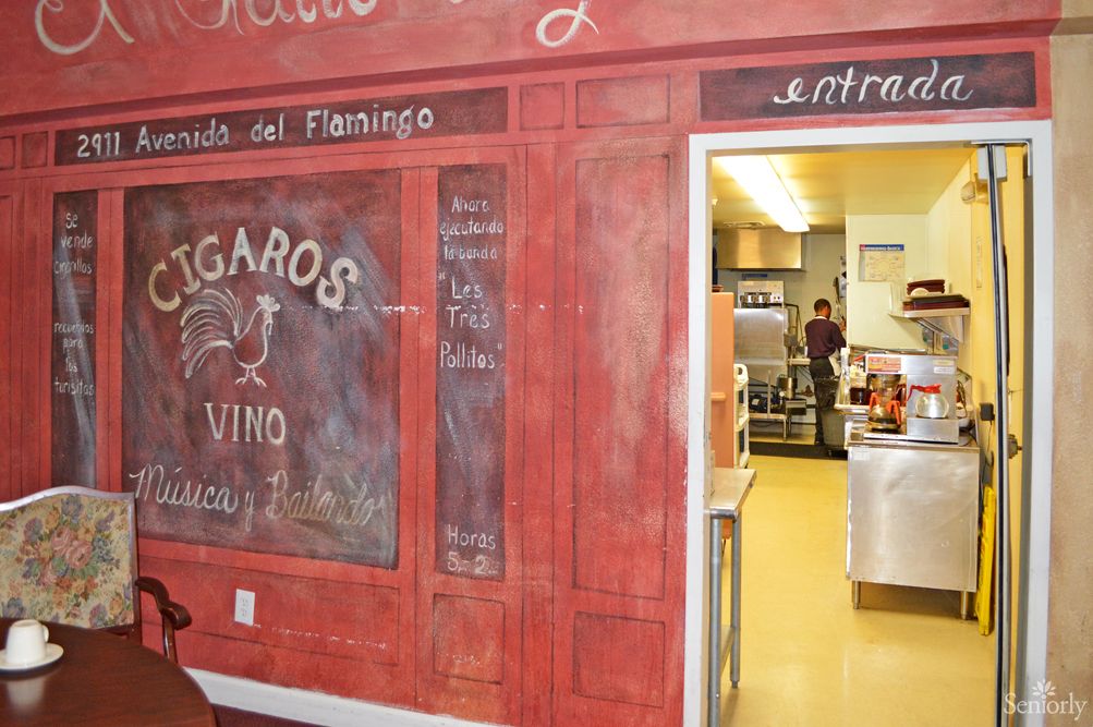 A view of a restaurant entrance with a chalkboard design and adjacent kitchen area.