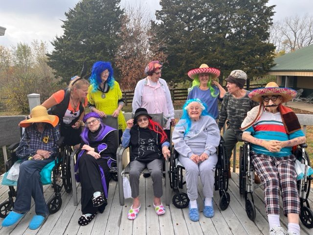 A group of people in colorful costumes and wigs, enjoying time outdoors together.
