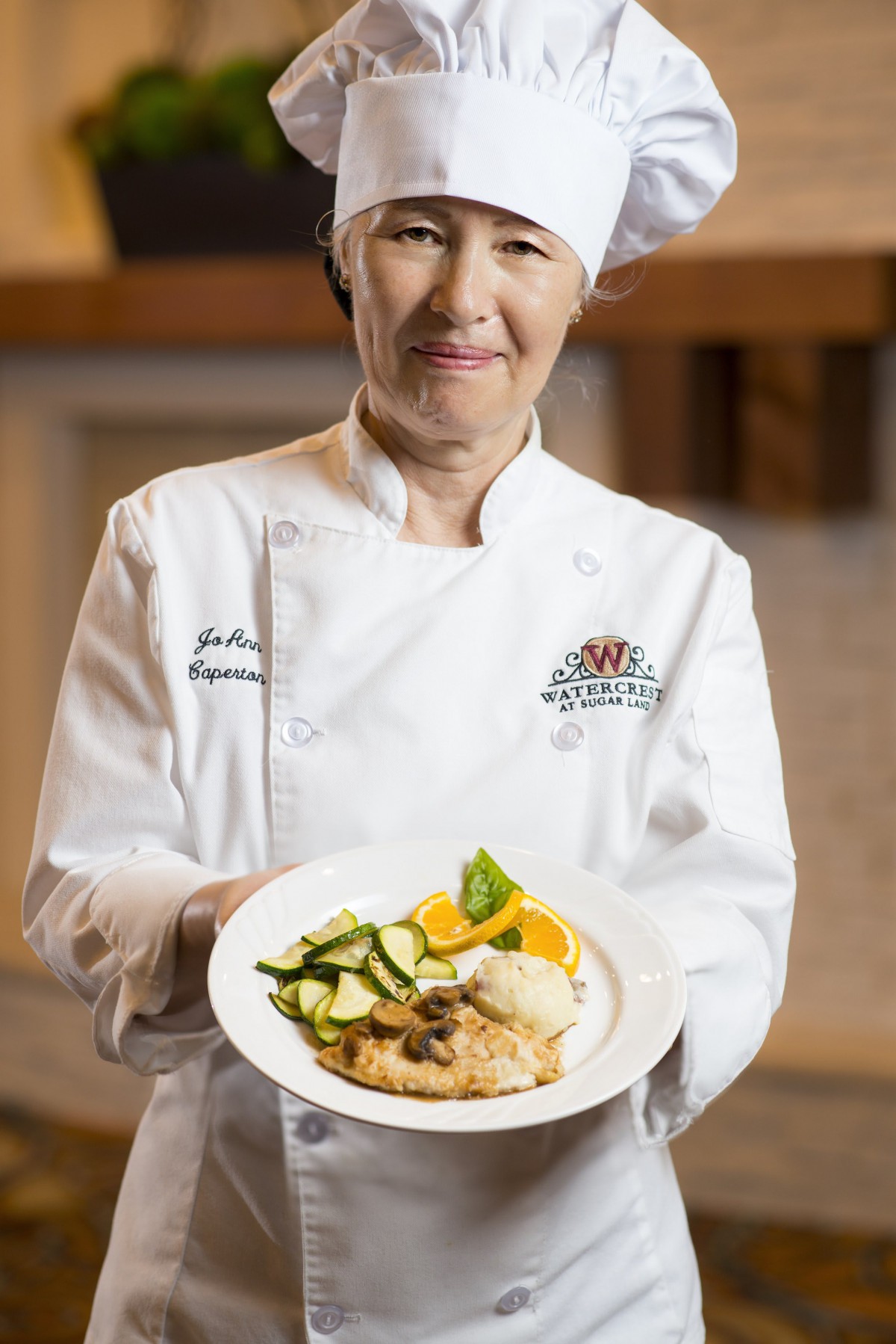 A chef proudly presenting a dish in a restaurant setting.