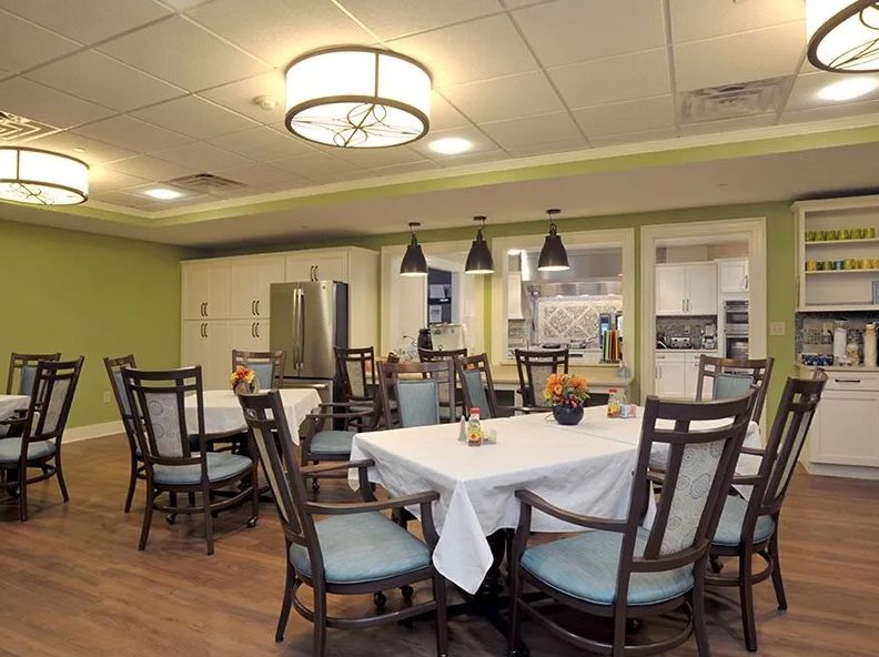 A well-decorated dining room with neatly arranged tables and modern lighting fixtures.