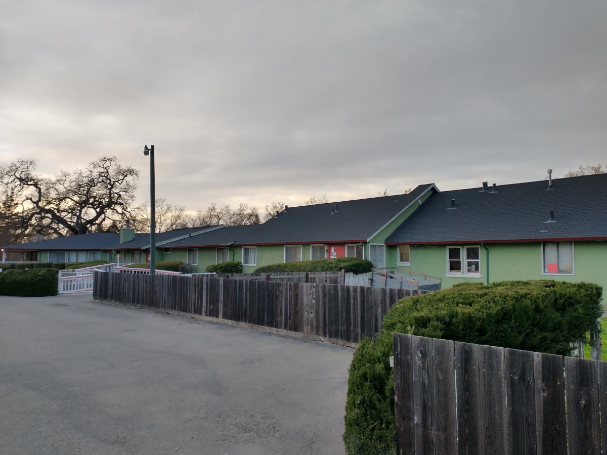 A row of houses with wooden fences under a cloudy sky in a suburban area.