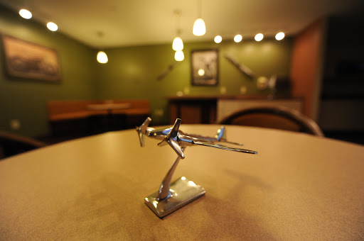 A metallic model airplane sits on a table in a cozy restaurant setting.