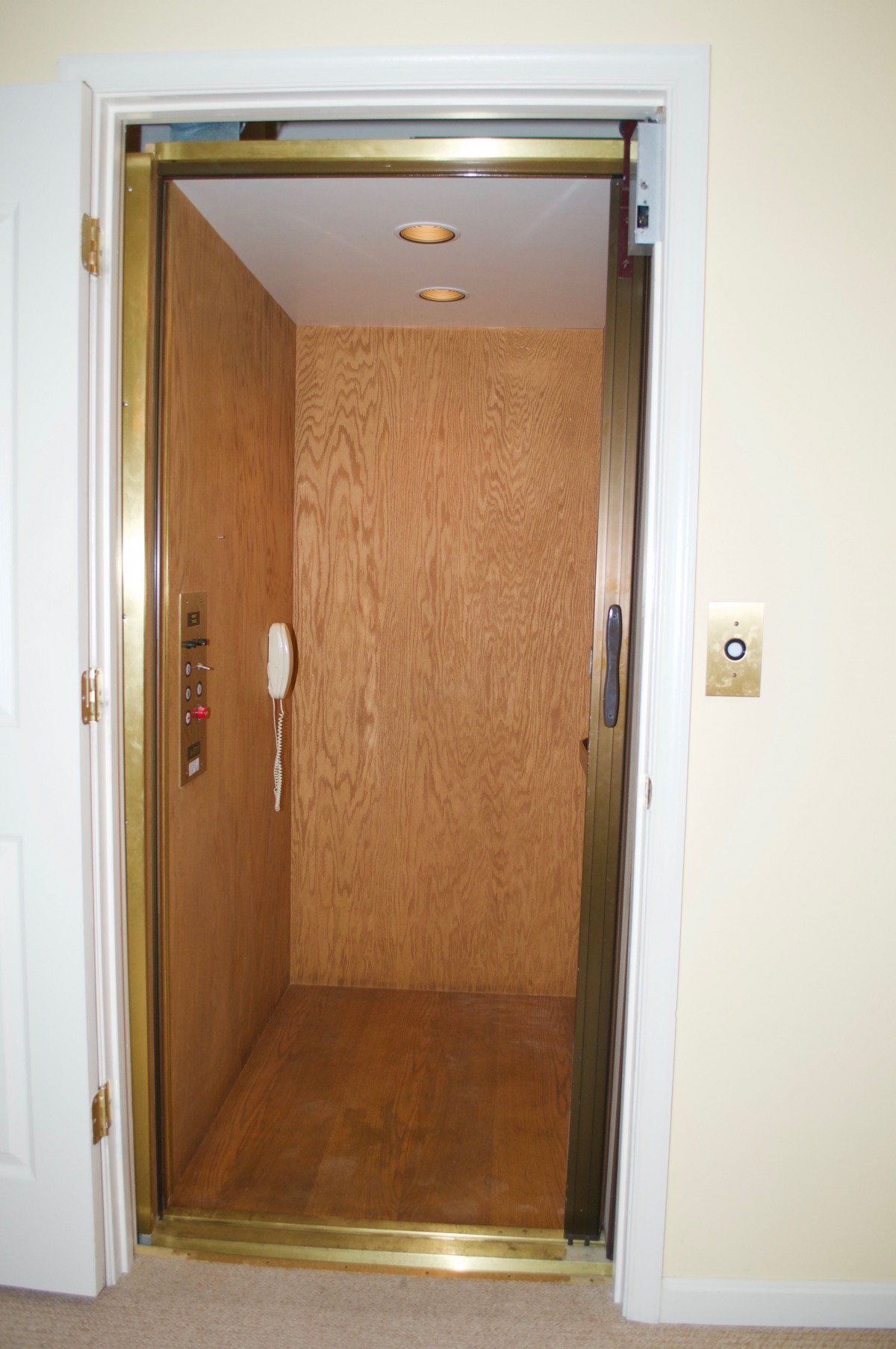 An interior view of an elevator with wooden paneling and control buttons.