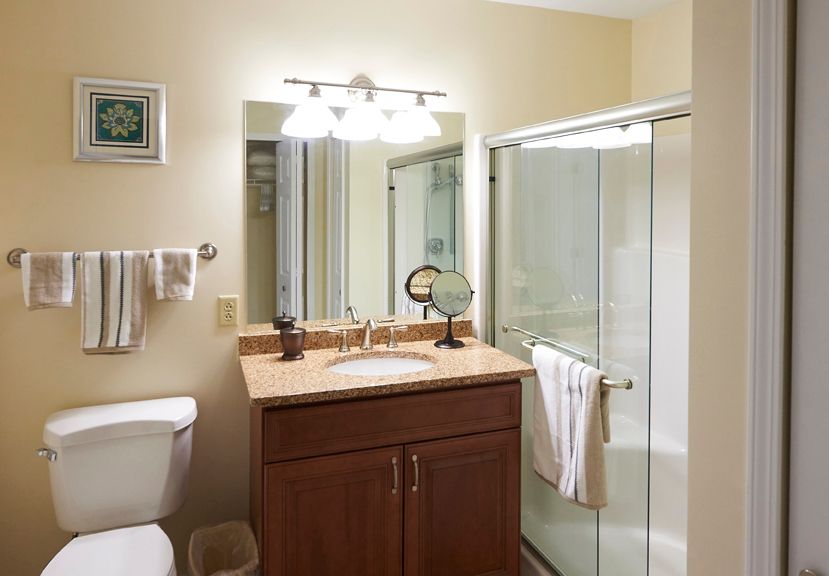 A neatly organized bathroom with a sink, mirror, and glass-enclosed shower.