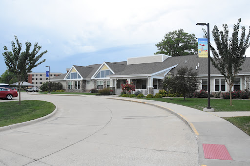 A modern residential building with a landscaped entrance under a cloudy sky.