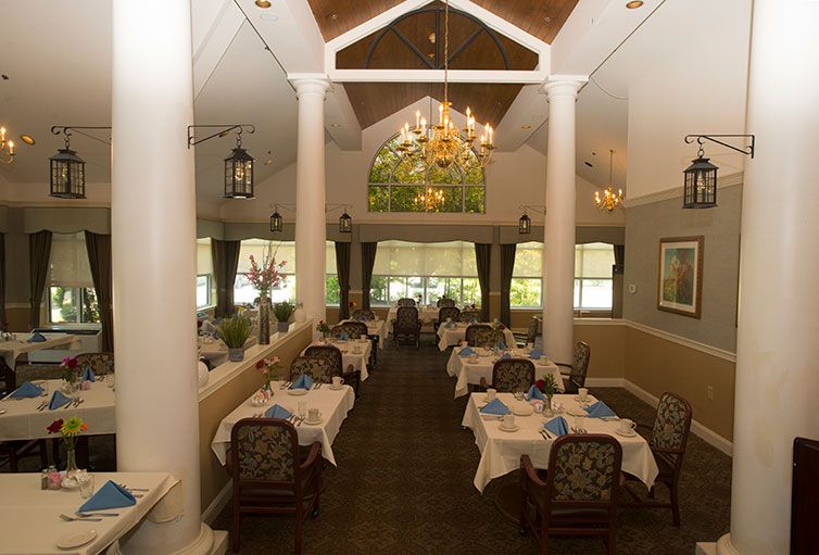 An elegant restaurant interior with neatly arranged tables and chairs, highlighted by a chandelier.