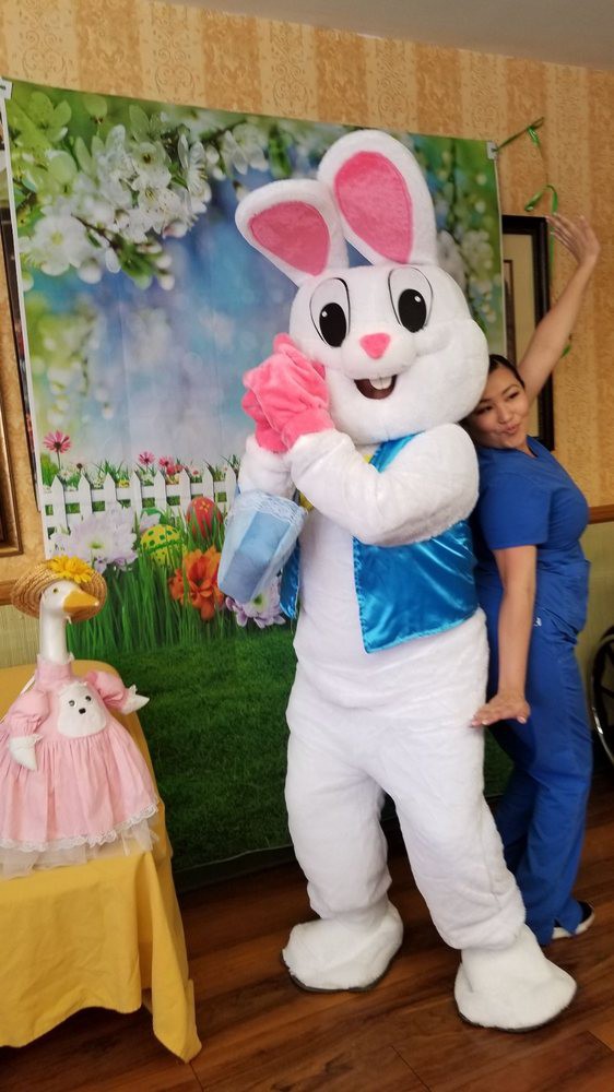 A person posing with an Easter bunny mascot in a festive setting.