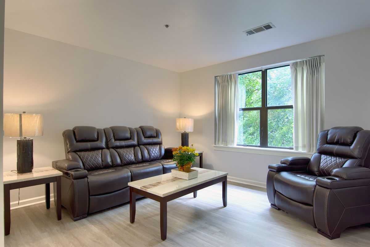 A minimalist living room with a leather sofa, armchair, and a coffee table near a window.