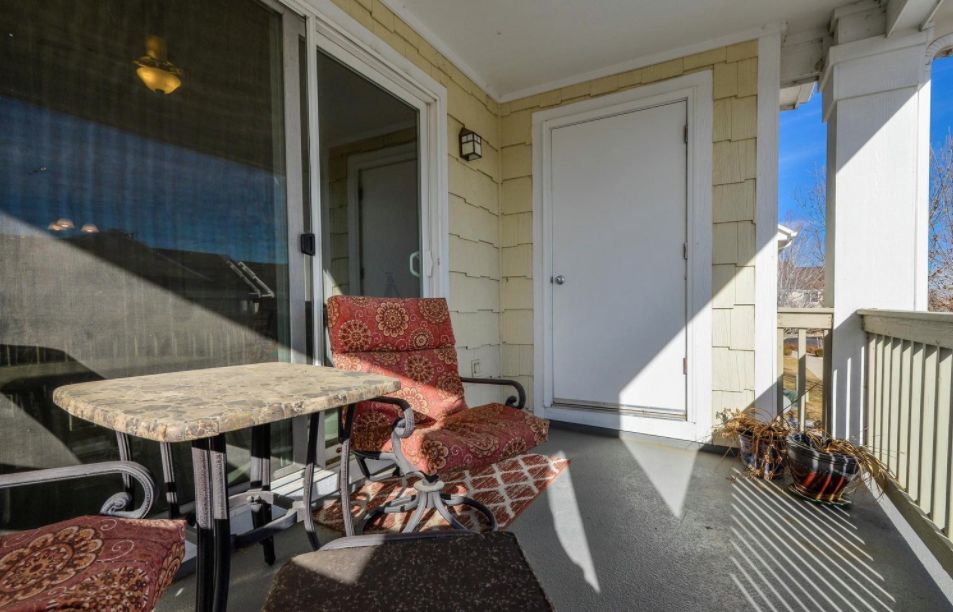 A cozy outdoor balcony with patio furniture and sunlight streaming in.