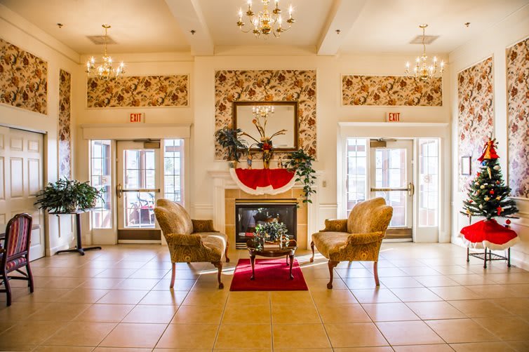 A luxurious lobby with elegant seating around a decorative fireplace, adorned with chandeliers and classic decor.