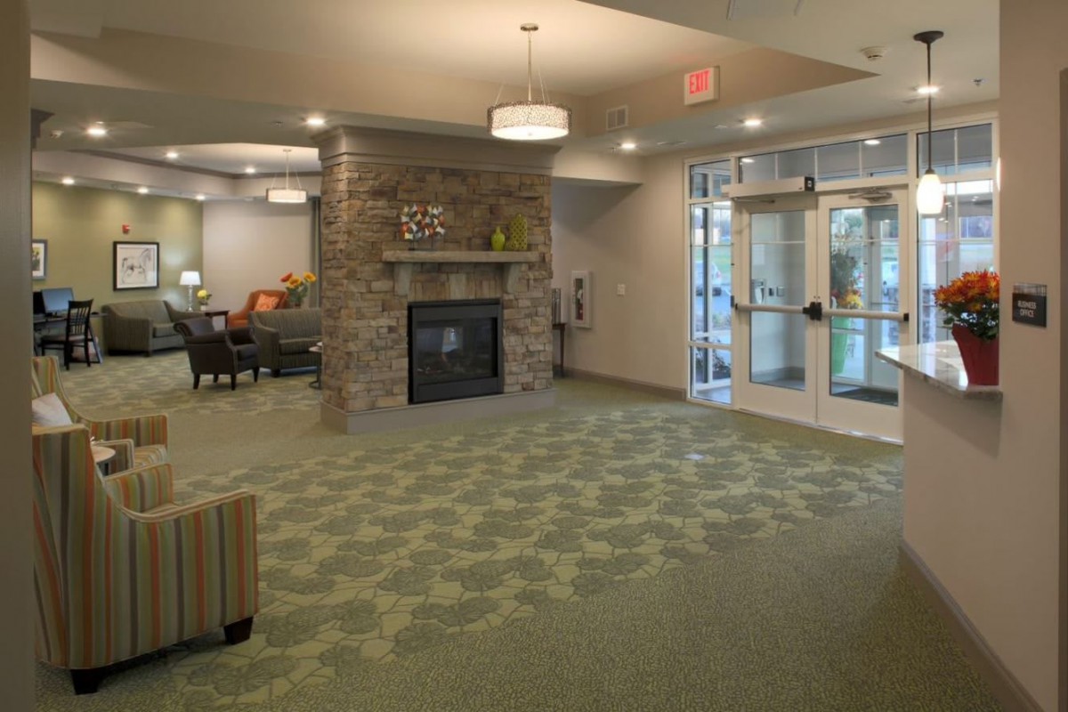 A cozy lobby with a stone fireplace, patterned carpet, and seating area.