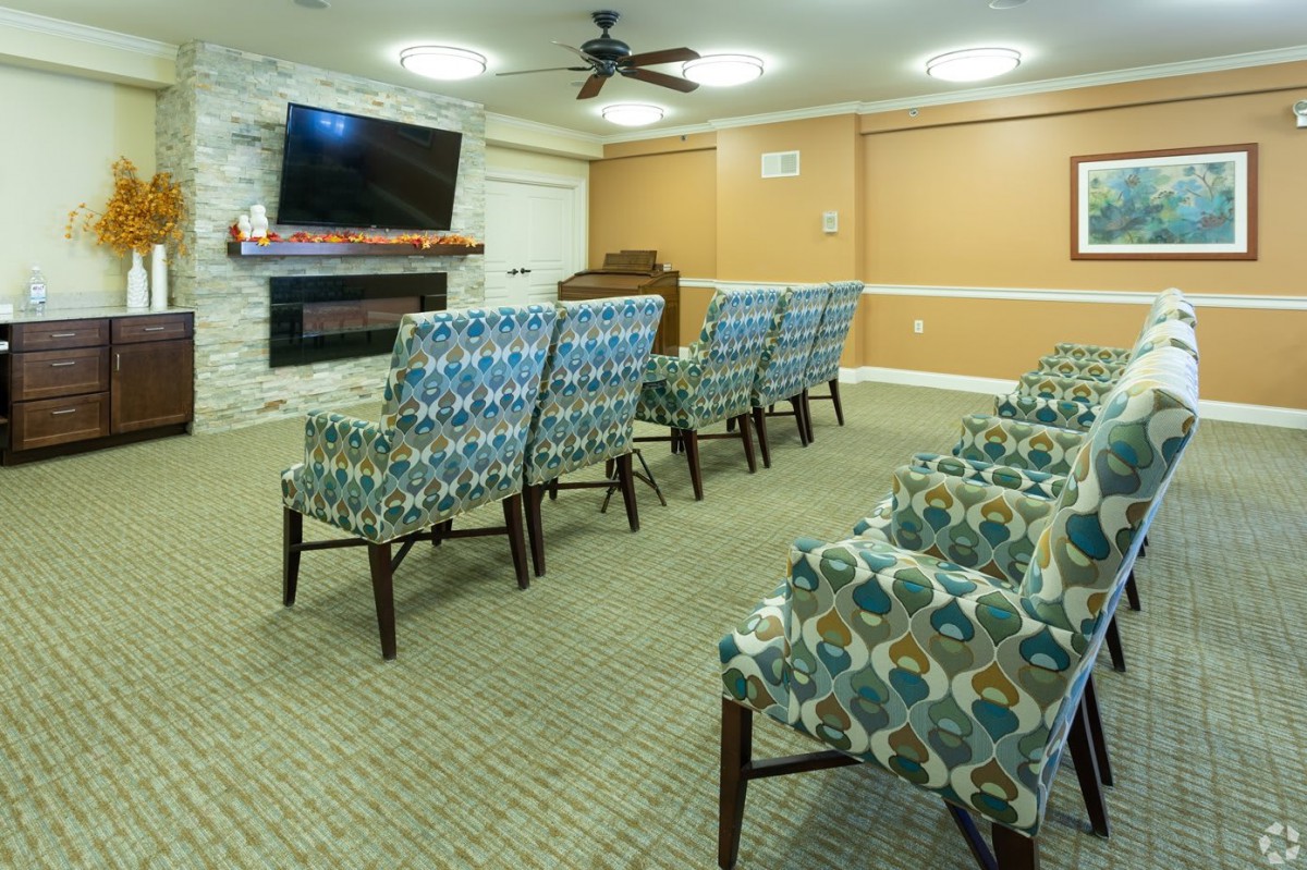 A cozy room with patterned chairs facing a television mounted on the wall.