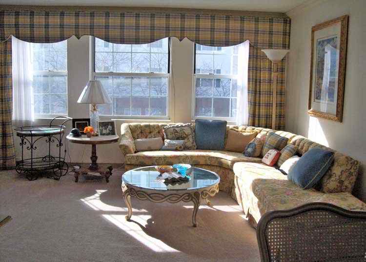 A cozy living room with a curved sofa and ample sunlight streaming through large windows.