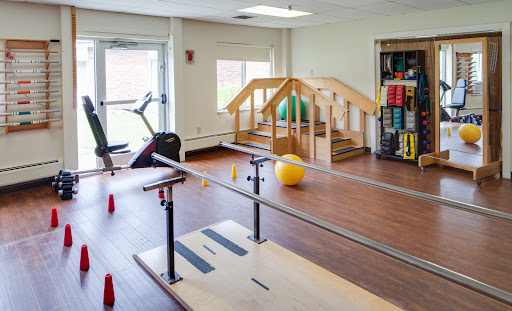A well-equipped rehabilitation space featuring exercise bars, a balance ball, and various fitness tools.