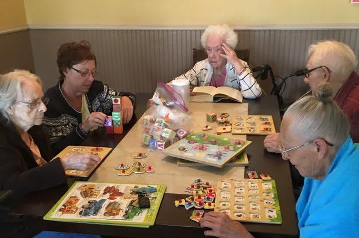 A group of seniors engaging in a puzzle activity at a table indoors.