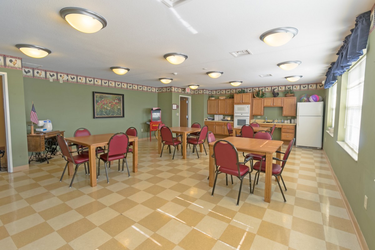 A spacious dining area with several tables and a kitchen in the background.