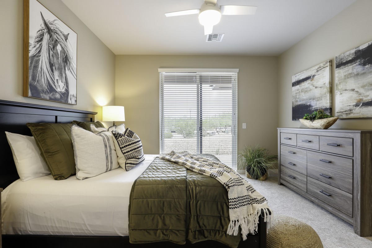A modern and minimalist bedroom featuring a neatly made bed, soft lighting, and large windows for natural light.