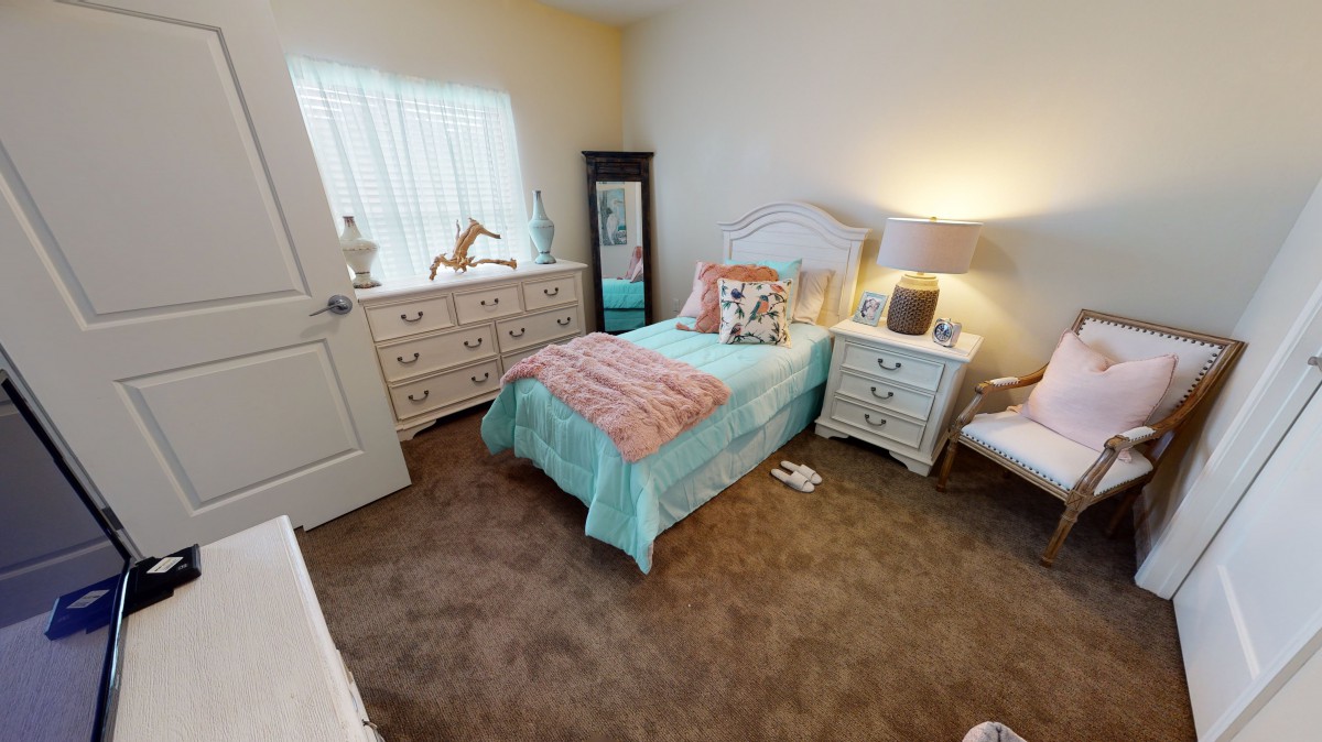 A cozy kids' bedroom with a single bed, dresser, and bedside lamp.
