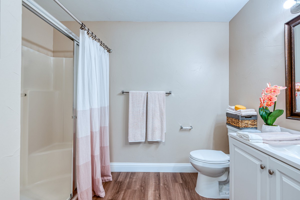 A modern bathroom with a shower, toilet, and towels neatly arranged.