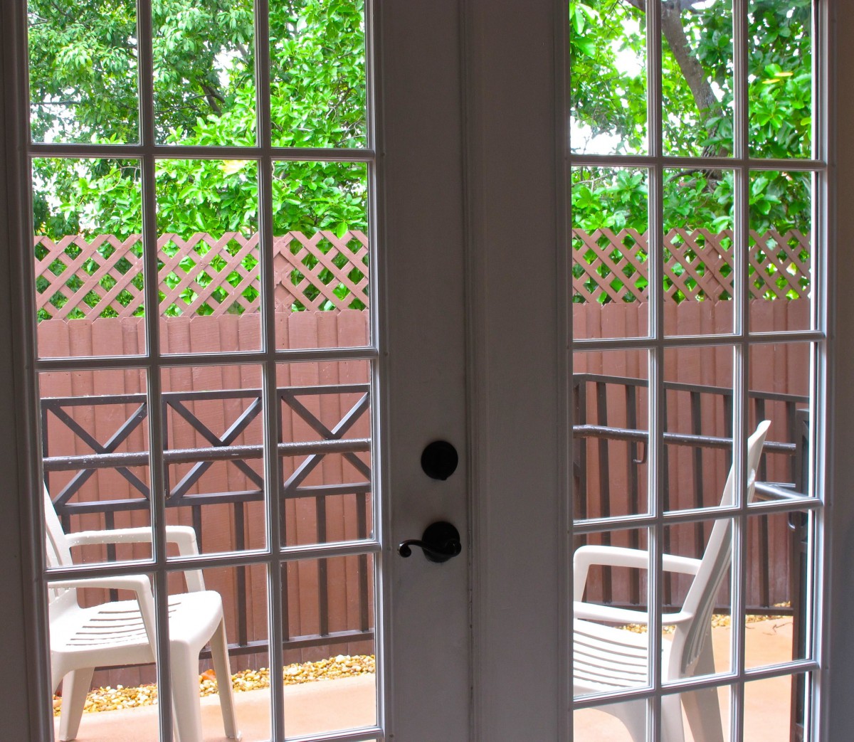 View of a cozy patio area with chairs, seen through glass doors on a bright day.