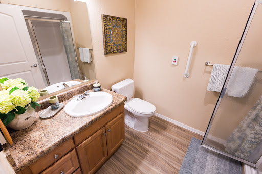 A modern bathroom featuring a sink, toilet, shower, and elegant wooden cabinetry.