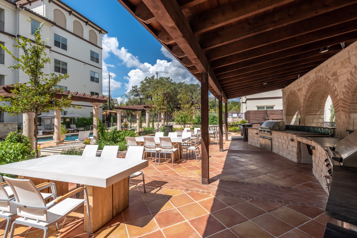 Outdoor patio with seating area and wooden pergola on a sunny day.