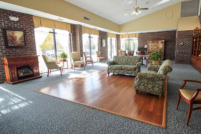 A spacious lobby with ample seating, featuring large windows and a mix of carpet and hardwood flooring.